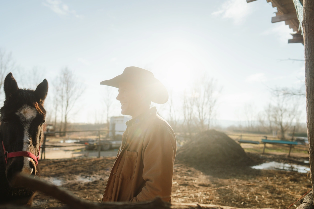We’re here to help Rancher standing beside a horse at Warrior Ranch